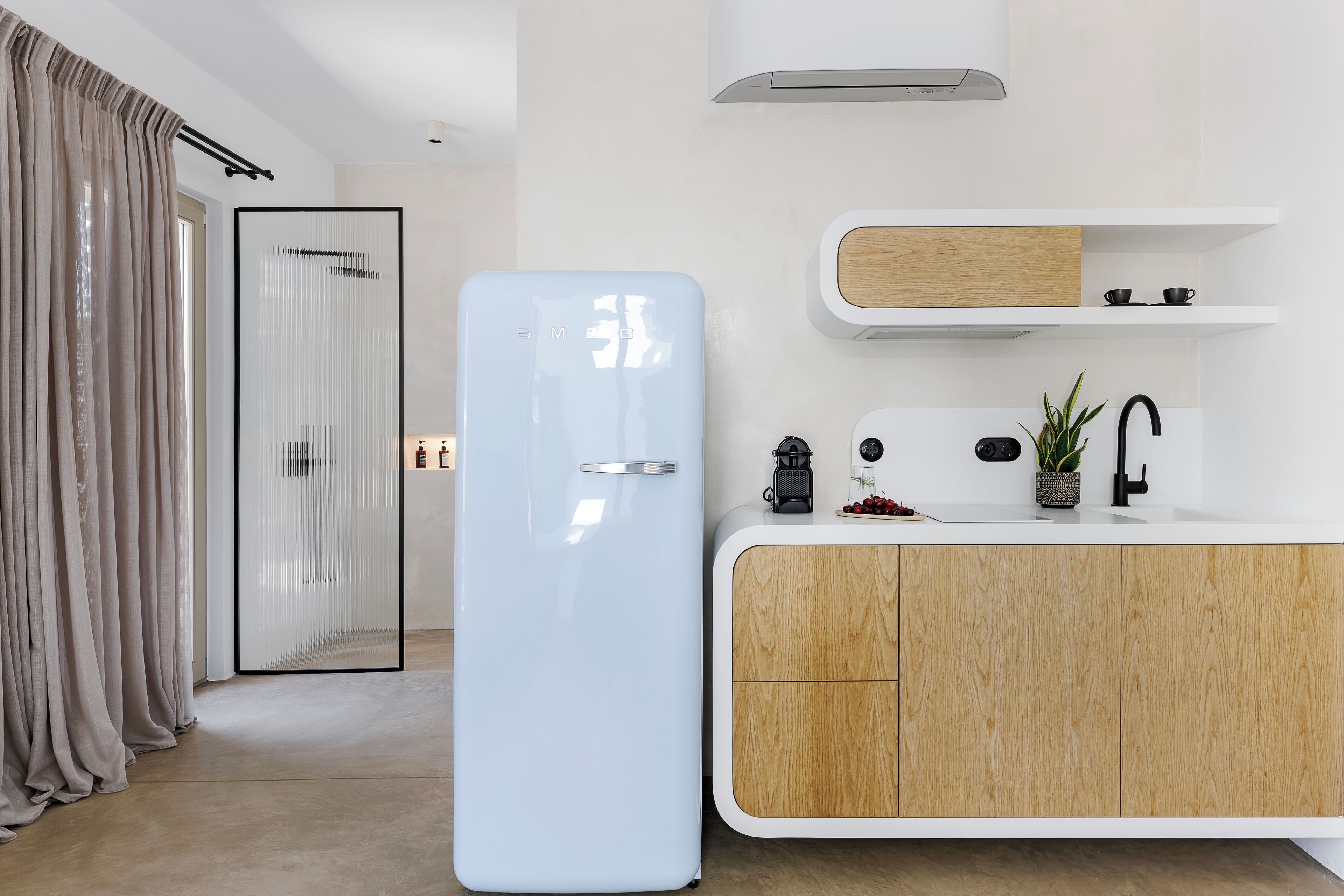 Una cocina moderna con un refrigerador azul claro, armarios de madera, una encimera blanca y un pequeño estante con utensilios de cocina.
