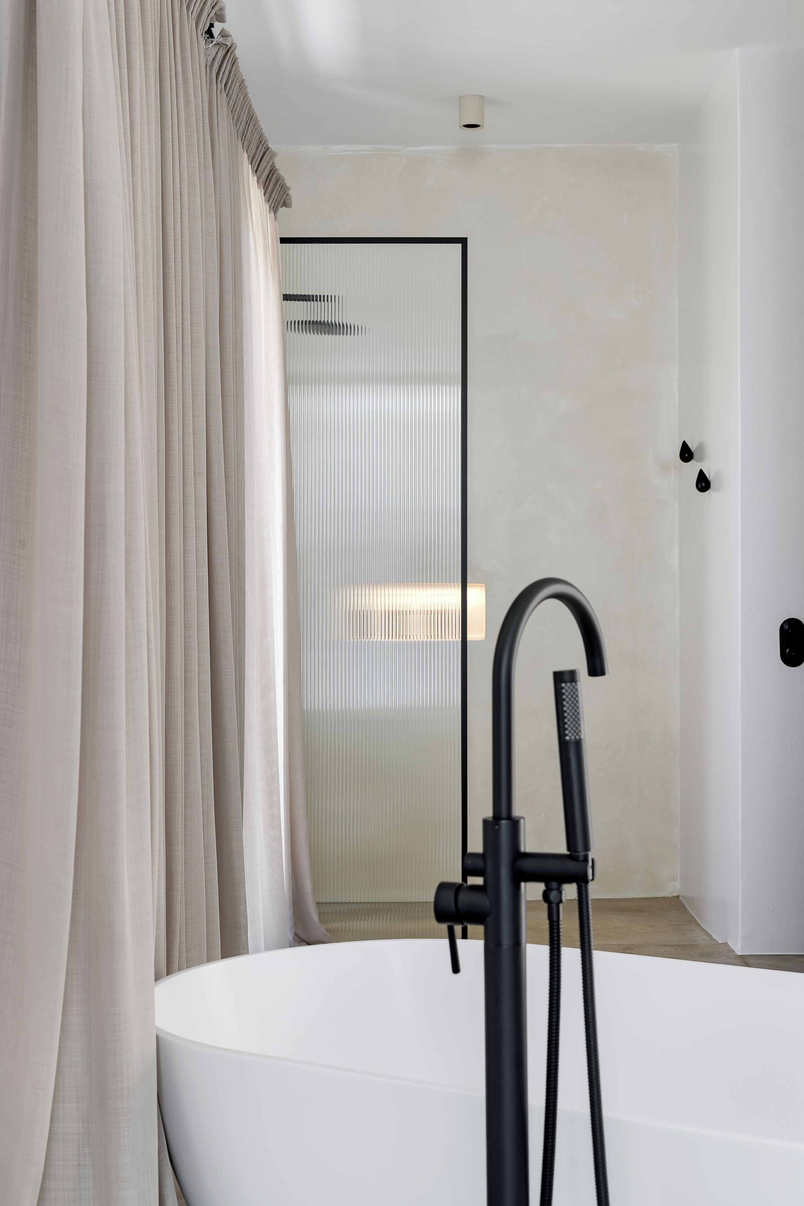A modern bathroom with a freestanding bathtub, a glass shower enclosure, and a curtain.