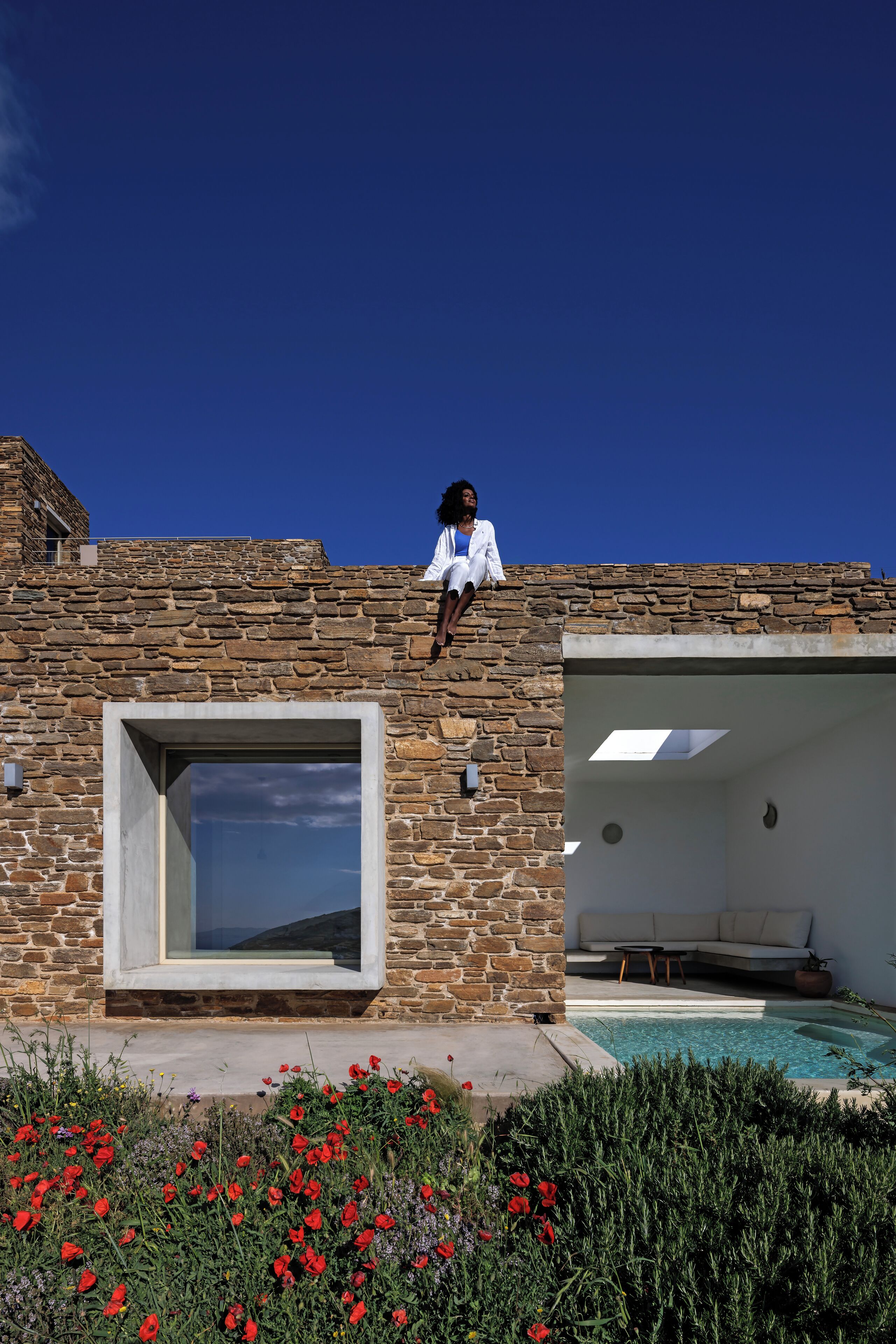 A stone building with a large window and a pool area.