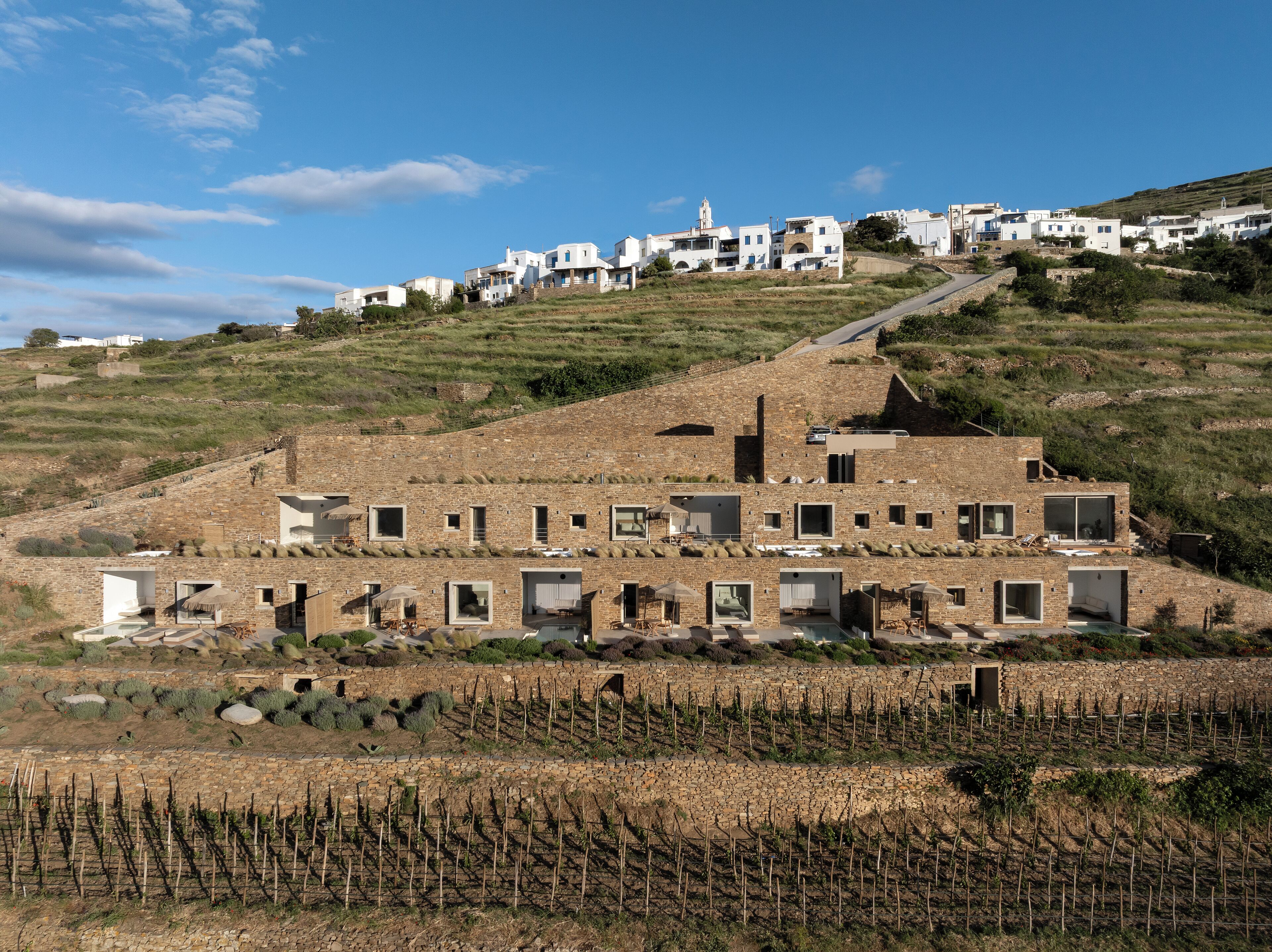 A hillside village with traditional white buildings, terraced vineyards, and a prominent church tower.
