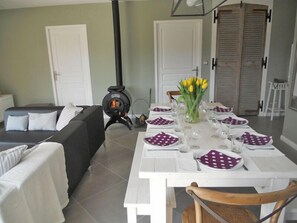 Un comedor con una mesa blanca dispuesta para cuatro personas, rodeado por un sofá y una chimenea.