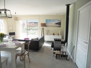 Una sala de estar moderna con un sofá, una mesa de comedor, sillas, un televisor y un cuadro en la pared.