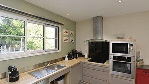 A modern kitchen with a stainless steel sink, a double oven, and a microwave.