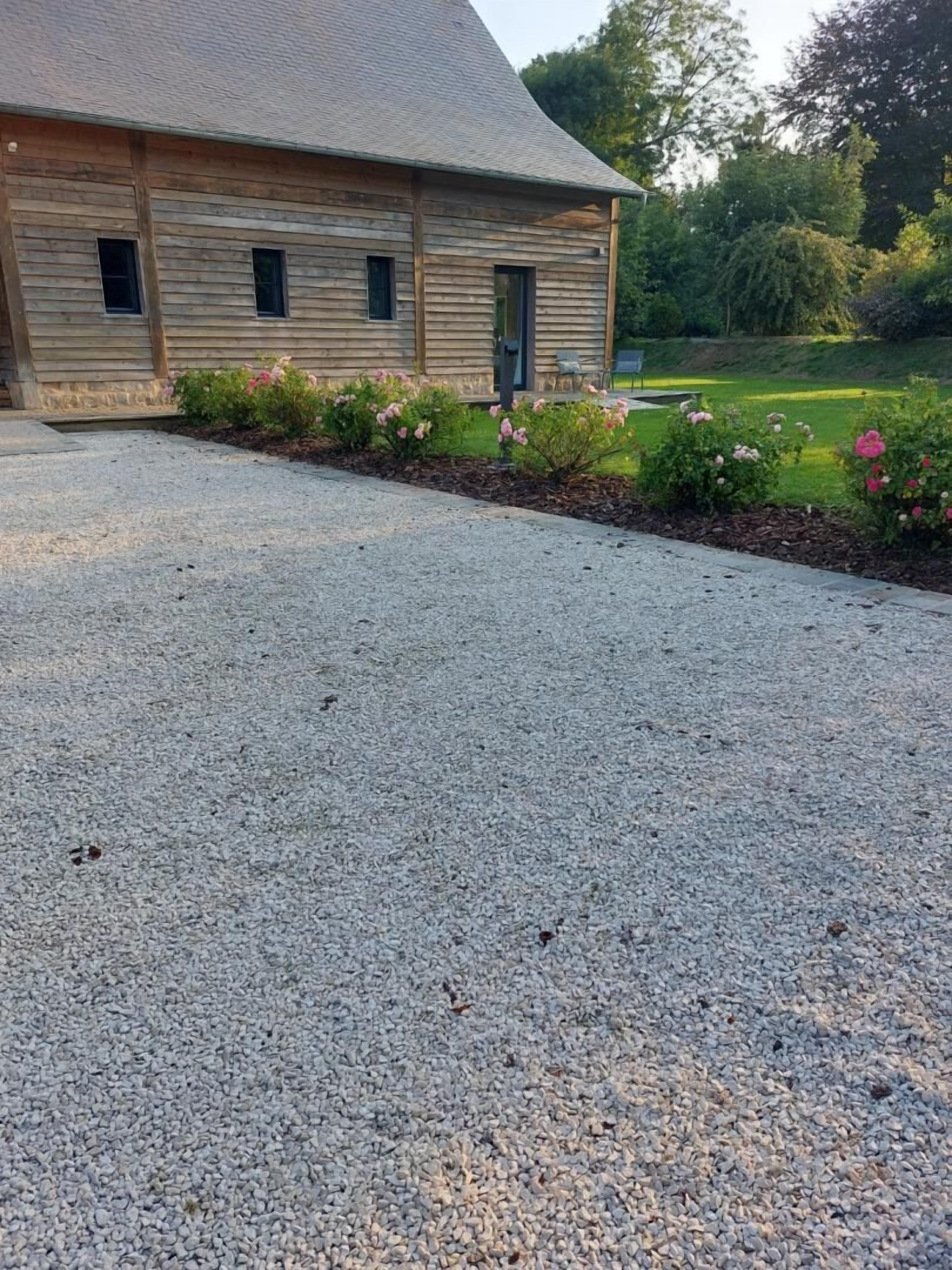 A gravel driveway leading to a wooden building with a sloped roof.