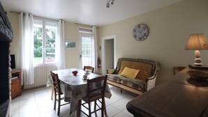 A dining area with a table, chairs, a sofa, and a lamp.