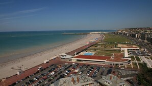 Eine Vogelperspektive auf eine Küstenstadt mit Strand, Parkplatz und Gebäuden.