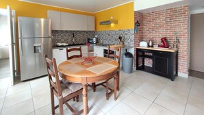 Cocina compacta con comedor, que incluye un refrigerador, microondas y una pared decorativa de ladrillo.