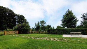 Un espacio al aire libre con césped, una valla de madera, una mesa de picnic y un seto.