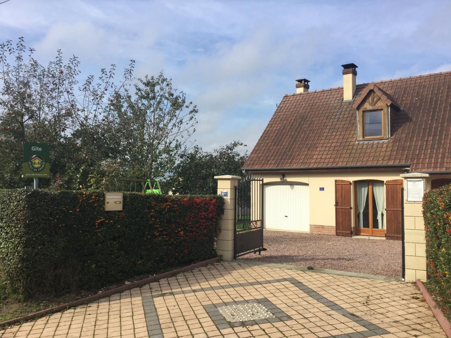 A two-story house with a tiled roof and a gated driveway.