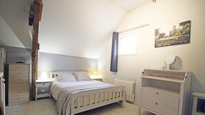 A bedroom with a bed, bedside tables, a dresser, a radiator, a window with a curtain, and a wall-mounted mirror. - Le Clos Saint-martin (AVESNES EN BRAY)