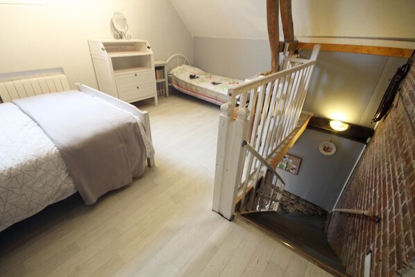 A bedroom with a bed, a nightstand, a dresser, and a small desk. There is a window with a view of the outside.
