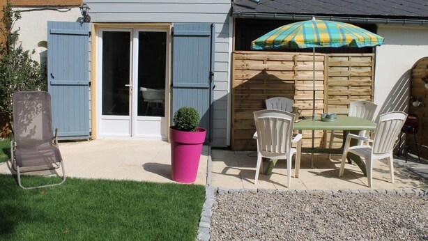 A patio with a table and chairs, a pink planter, and a wooden fence. - Le Clos Saint-martin (AVESNES EN BRAY)