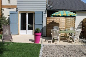 A patio with a table and chairs, a pink planter, and a wooden fence.