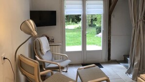A room with a bed, a bedside table, a chair, a television, and a sliding glass door leading to a balcony. - Le Clos Saint-martin (AVESNES EN BRAY)