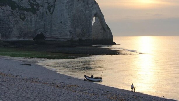 A beach with white cliffs, a boat on the shore, and a person standing by the water. - Le Doris - Vattetot SUR MER (VATTETOT SUR MER)