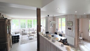 A spacious living area with a large window, a dining area with a long counter, and a kitchen with wooden paneling. - Le Doris - Vattetot SUR MER (VATTETOT SUR MER)