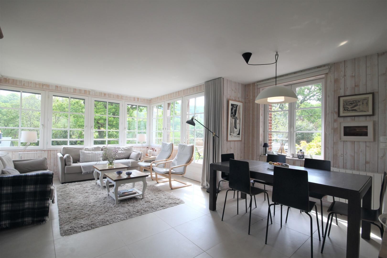 A spacious living room with a large window, a dining area, and a cozy seating arrangement.
