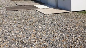 A row of beach huts with white walls and colorful roofs, lined up on a gravel beach with cliffs in the background. - Les Ramiers - Criel SUR MER (CRIEL SUR MER)