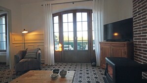 A living room with a fireplace, a television, a sofa, and a dining table with bowls. - Les Ramiers - Criel SUR MER (CRIEL SUR MER)