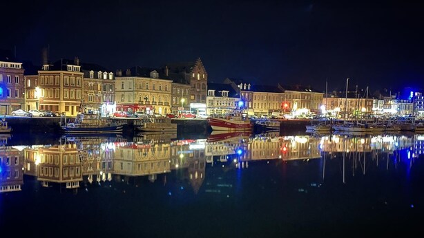 A nighttime view of a harbor with buildings reflecting on the water. - Norwegian Stern - Fecamp (FECAMP)