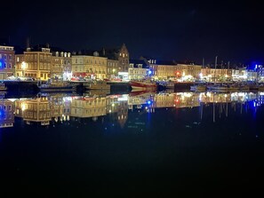 A nighttime view of a harbor with buildings reflecting on the water.