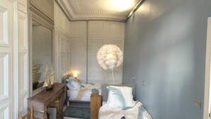 A room with a bed, a wooden dresser, a mirror, and a decorative light fixture. - Norwegian Stern - Fecamp (FECAMP)