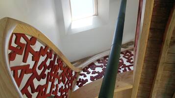 Una scala in legno con ringhiera a motivi geometrici e un piccolo lucernario.