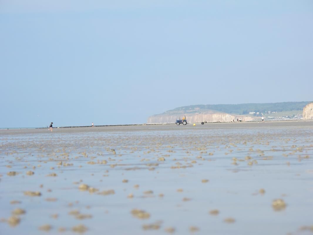 Une plage avec un tracteur et une personne au loin.