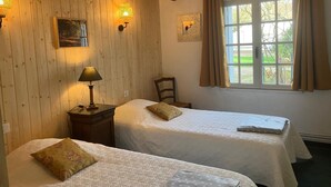 A room with two beds, wooden walls, a window with curtains, and wall-mounted lamps. - Chateau de La Croix Blanche (ST ARNOULT)