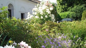 A garden with various flowers and a building in the background. - Chateau de La Croix Blanche (ST ARNOULT)