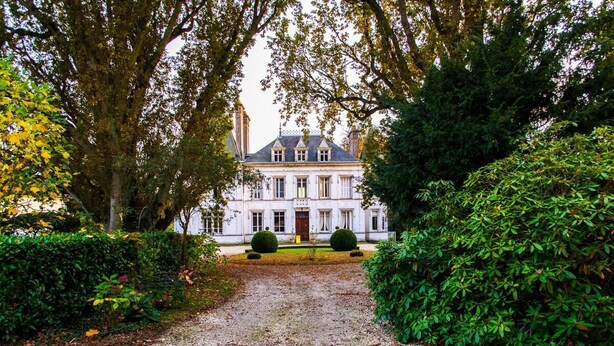 A large, symmetrical building with a central entrance, surrounded by well-maintained hedges and trees. - Chateau de La Croix Blanche (ST ARNOULT)