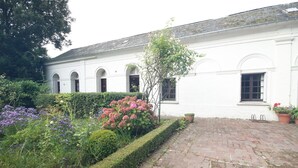 A white building with arched windows and a brick pathway leading to it. - Chateau de La Croix Blanche (ST ARNOULT)