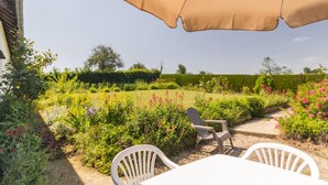 A patio with a table and chairs, surrounded by a garden with various plants and flowers. - Le Bremontier - Massy (MASSY)