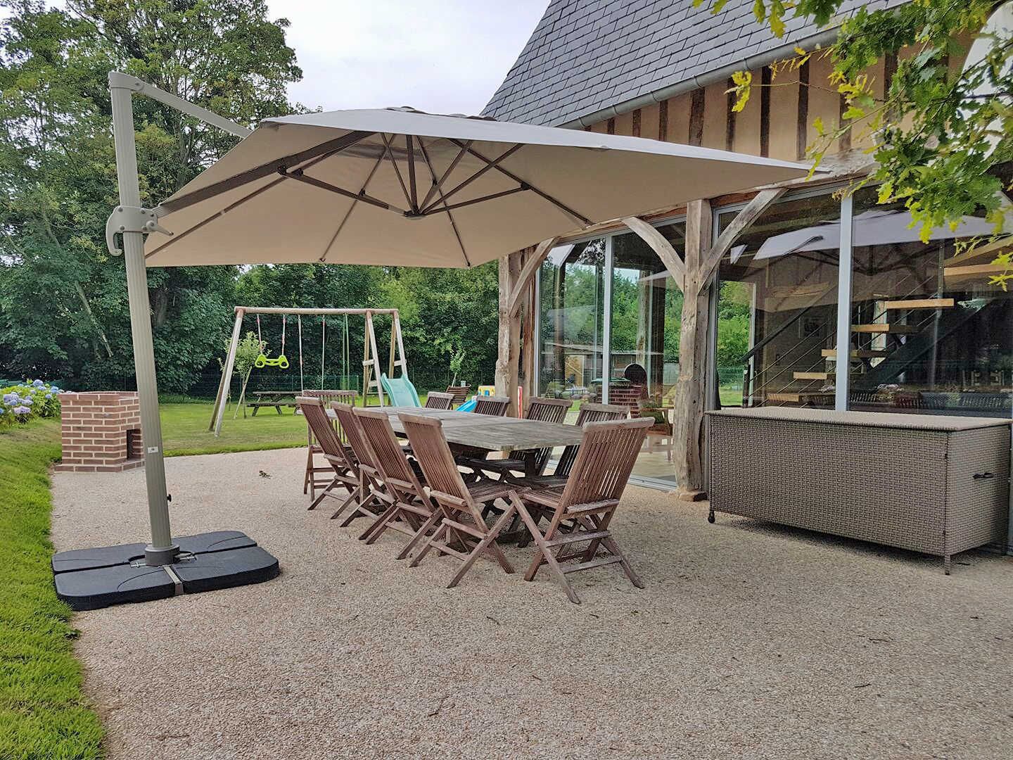 An outdoor patio with a table and chairs, a swing set, and a brick fireplace.