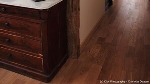 Une pièce avec une commode en bois, un grand miroir doté d’un cadre décoratif et une poutre en bois au plafond.