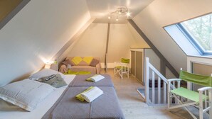 A cozy attic bedroom with two beds, a small table, and a chair.