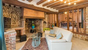 A cozy living area with a stone fireplace, wooden beams, and a white sofa. - Le 1722 - Vittefleur (VITTEFLEUR)