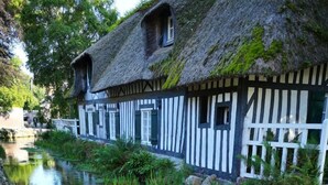 A traditional half-timbered house with a thatched roof, a narrow waterway, and a stone pathway. - Le 1722 - Vittefleur (VITTEFLEUR)