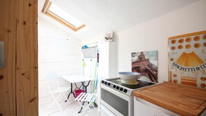 Una cocina con estufa blanca, encimera de madera y ventana sobre el fregadero.