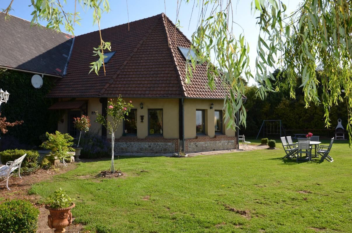 A house with a tiled roof, a small garden, and outdoor furniture.