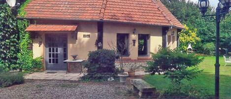 A house with a red-tiled roof, a small porch, and a gravel driveway.