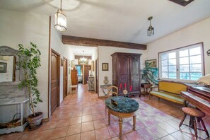 A spacious living room with a piano, a dining table, and a large window.
