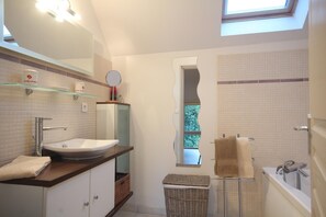 A modern bathroom with a large sink, a mirror, a window, and a bathtub. - Gîtes de France® - Le Héron (ST SAENS)