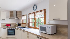 A modern kitchen with a built-in oven, microwave, sink, and wooden cabinets.
