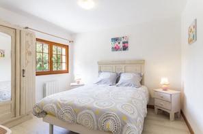 Une chambre à coucher avec un lit, deux tables de chevet, une fenêtre et une porte.