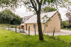 Une maison de plain-pied avec un toit en pente, un porche à l’avant et une cour clôturée.