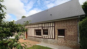 A traditional half-timbered house with a stone foundation and a grey tiled roof.