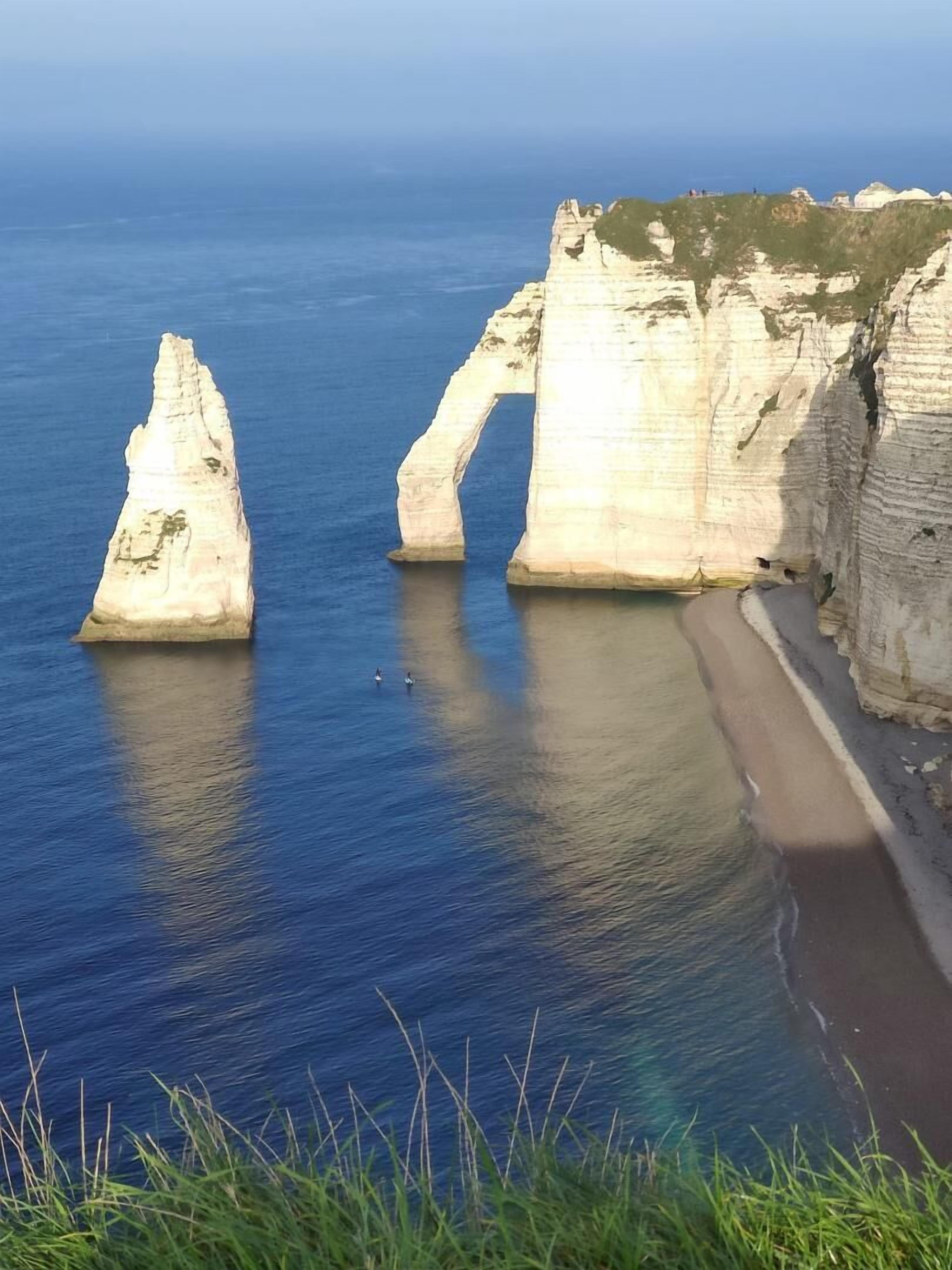 A coastal landscape with white cliffs and a sandy beach.