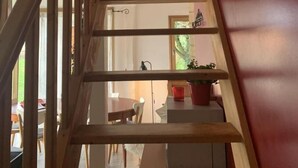 Una escalera de madera con barandilla que lleva a una habitación con una mesa y sillas de comedor.