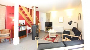Una sala de estar acogedora con chimenea, una escalera, un sofá y un televisor.